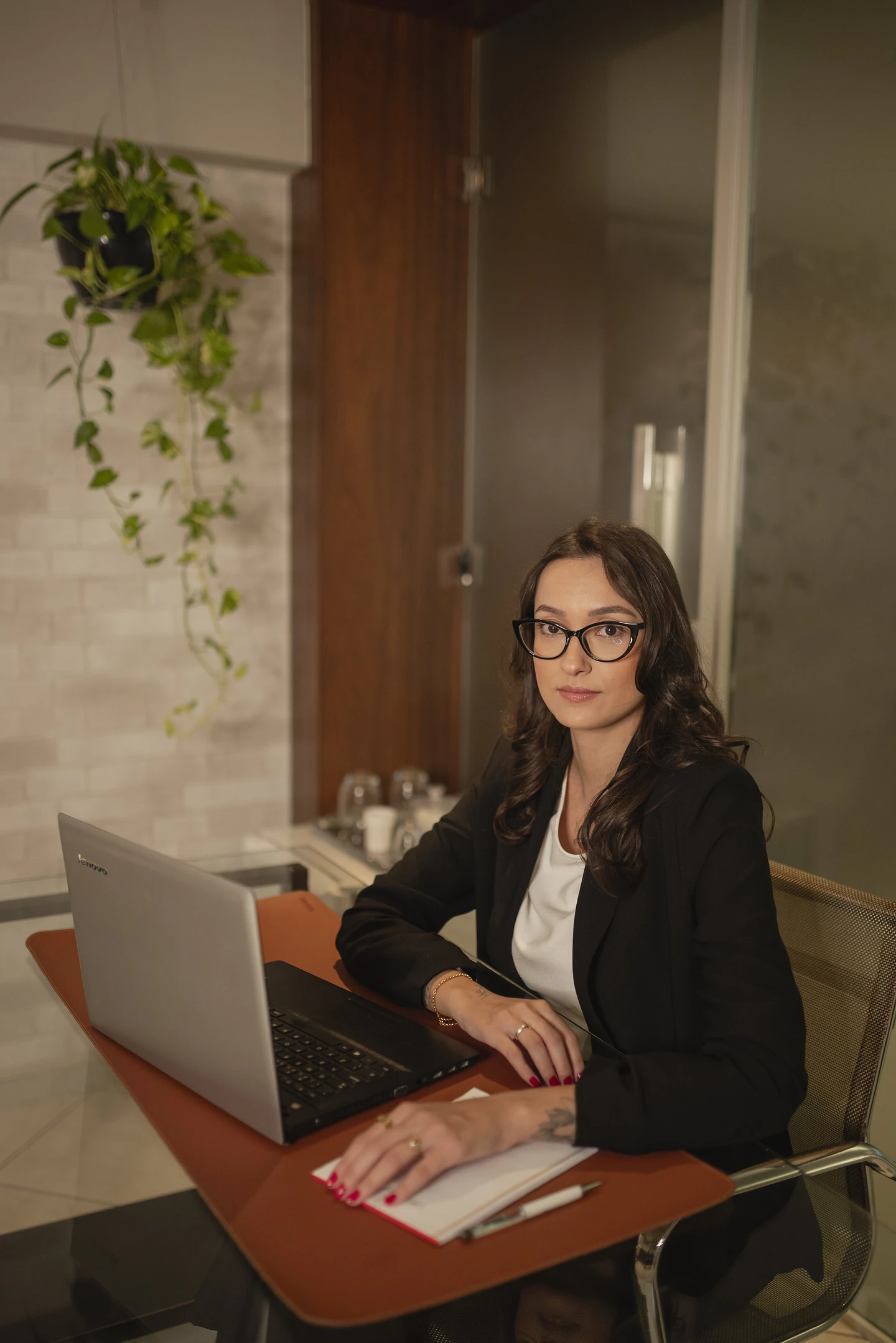 Ana Carla em seu ambiente profissional, sentada à mesa de trabalho